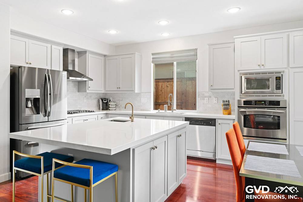 Modern kitchen featuring white cabinetry, quartz countertops, and vibrant blue bar stools