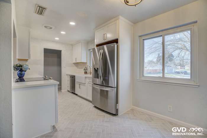Modern kitchen renovation featuring white cabinetry, herringbone tile flooring, and stainless steel appliances in Fair Oaks
