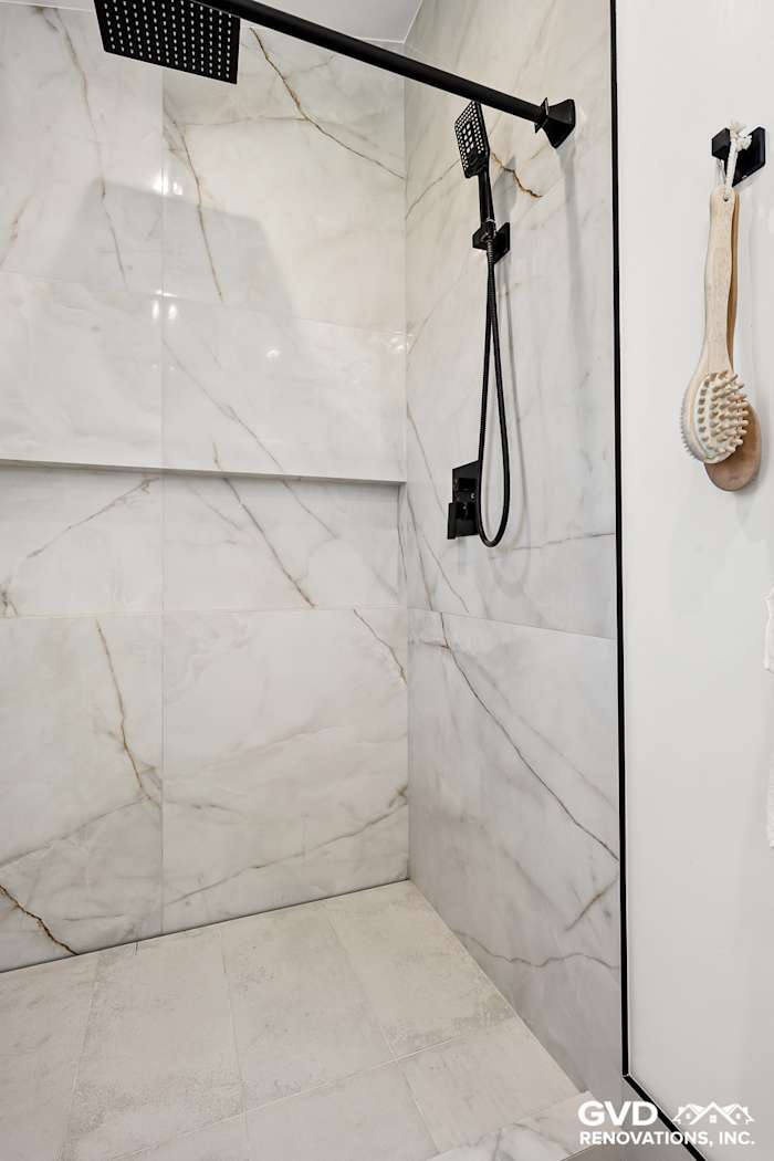 Luxurious marble shower with black fixtures and minimalist design in renovated Antelope bathroom