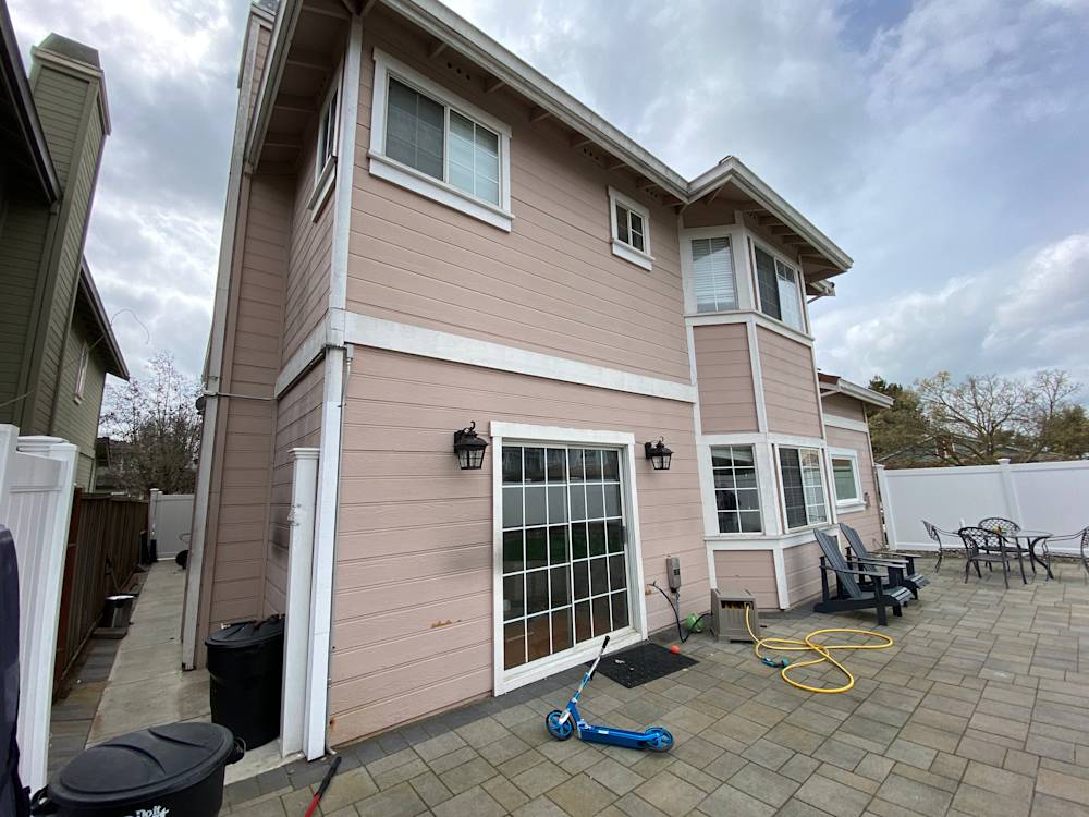 Light pink siding and stone paver patio in Sacramento, featuring a spacious outdoor area and landscaping