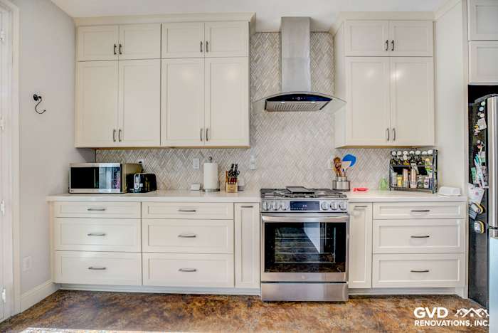 Modern kitchen remodel featuring white cabinets, a stainless steel range hood, and hexagon backsplash in Roseville, CA