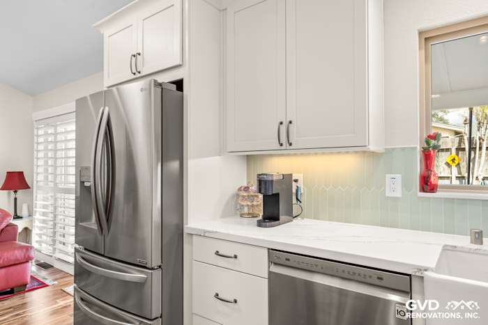 Modern kitchen with custom white cabinets, stainless steel appliances, and a green backsplash in Carmichael, CA