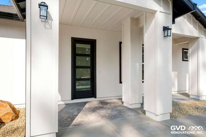 Modern entrance of a new construction home in Paradise, CA with sleek black door and stone pathway