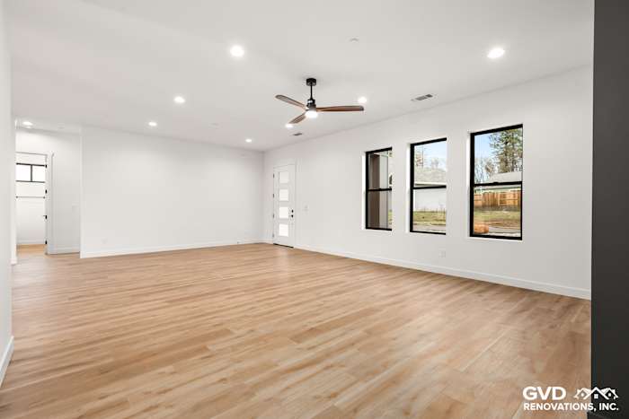 Spacious living room with high ceilings, large windows, and light wood flooring in new construction home