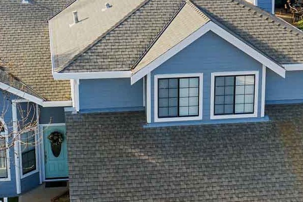 Modern home exterior featuring LP SmartSide siding in blue, landscaped yard, and double garage