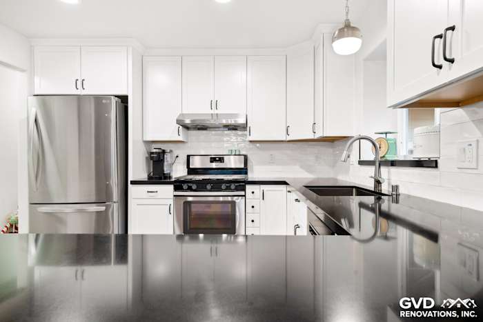 White shaker kitchen with stainless steel appliances, black countertops, and modern fixtures in Loomis remodel