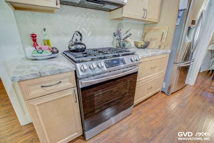 Modern kitchen with quartz countertops, stainless steel stove, and herringbone backsplash in Sacramento remodel