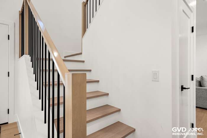 Modern staircase with hardwood steps and black railings, featured in a home remodel in Antelope, CA
