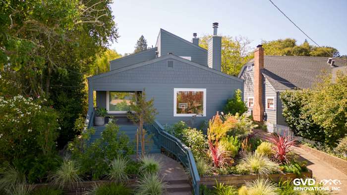 Corte Madera home featuring James Hardie Evening Blue siding and Arctic White trim, surrounded by lush landscaping