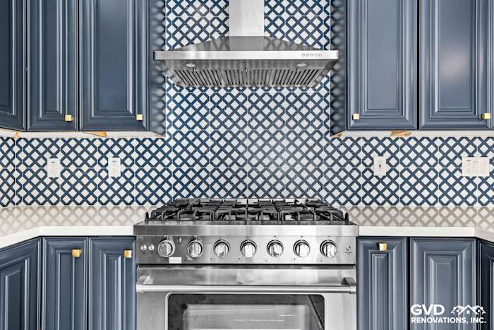Blue cabinetry with a stainless steel gas range and a patterned backsplash in an elegant Sacramento kitchen remodel