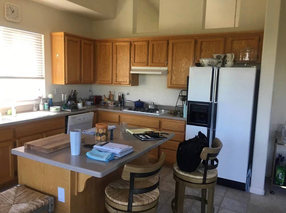 Outdated kitchen with oak cabinets, beige walls, and cluttered countertops