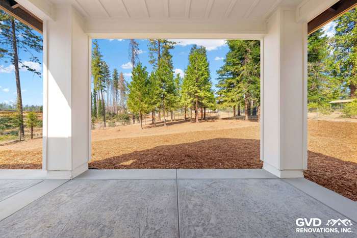 View from a porch featuring concrete flooring and large openings, overlooking a forested area with trees in Paradise, CA
