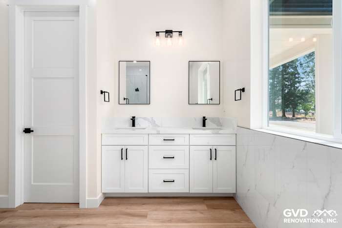 Modern bathroom with white cabinetry, dual sinks, marble accents, and stylish mirrors in Paradise, CA