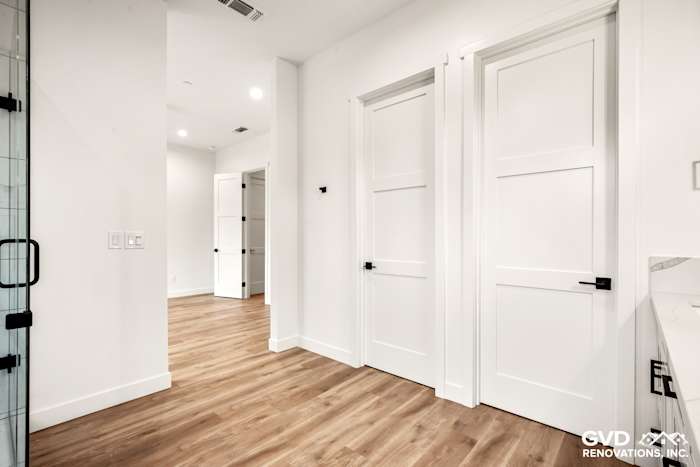 Modern bathroom entry in a new Paradise home, featuring white walls, elegant doors, and hardwood flooring