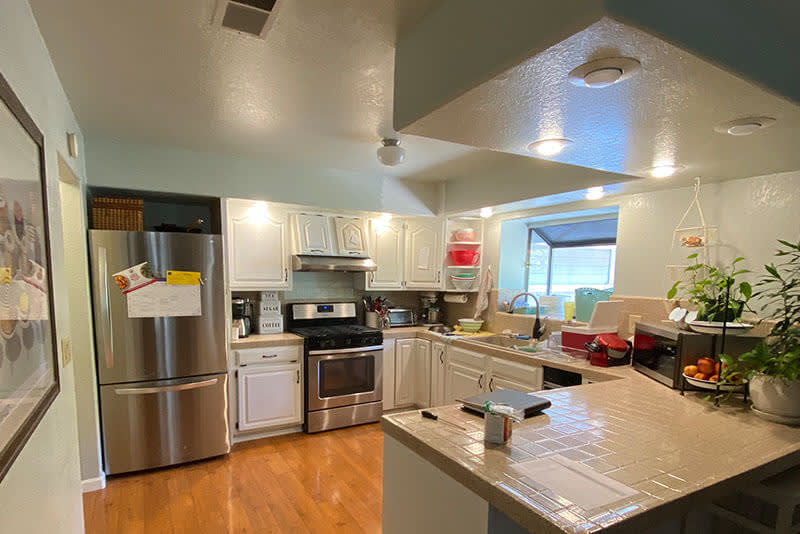 Outdated kitchen with light wood cabinetry, beige countertops, and older appliances