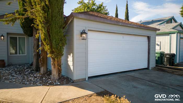 Updated garage exterior with James Hardie siding, featuring a new white garage door and landscape