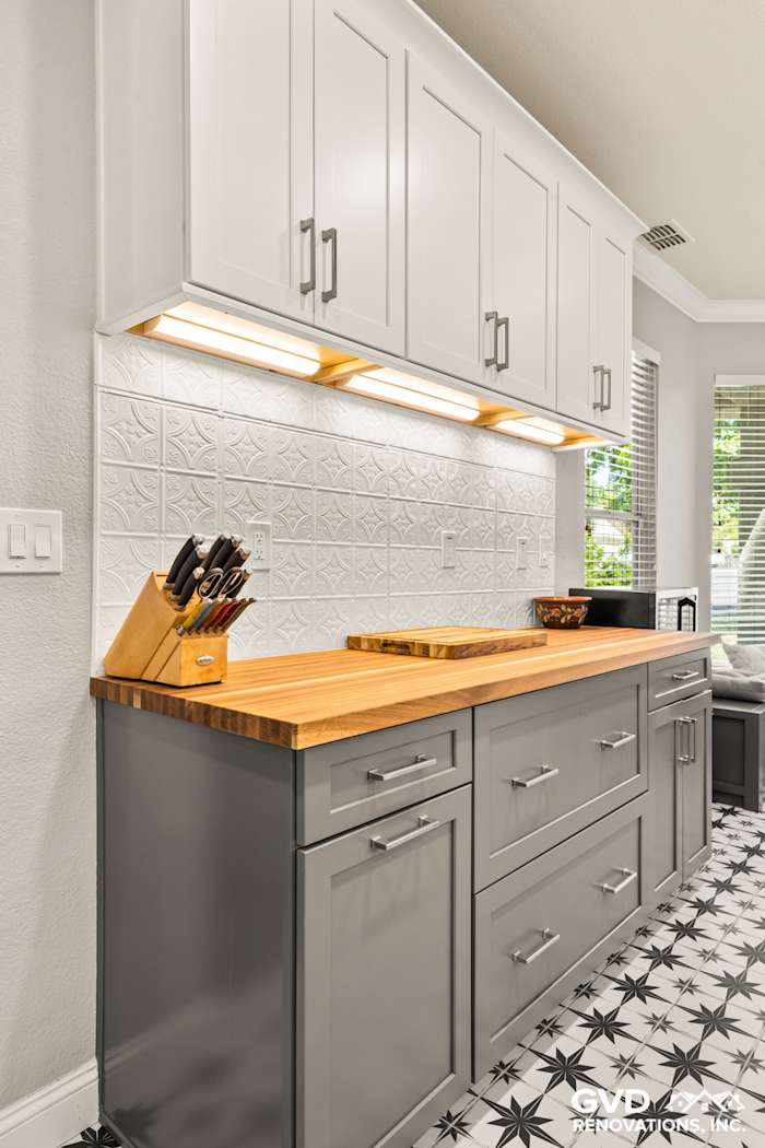 Modern kitchen remodel featuring gray cabinetry with wood countertops and patterned black-and-white tile flooring in Folsom