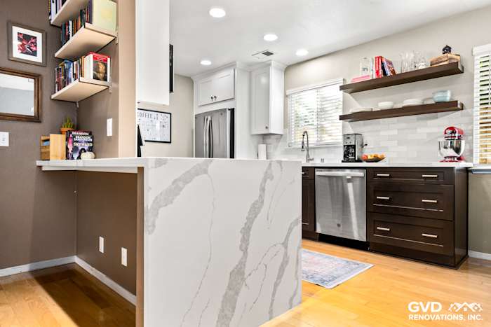 Modern kitchen remodel in Davis featuring quartz island, dark cabinetry, and open shelving