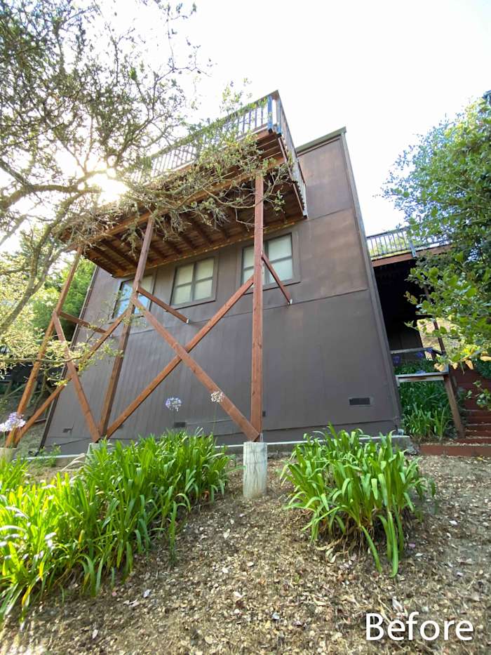 Before photo of a home exterior with untreated wood siding and overgrown landscaping in Mill Valley