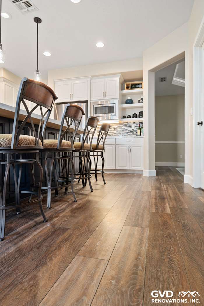 Modern kitchen remodel in El Dorado Hills with wooden floors, white cabinetry, and stylish bar stools