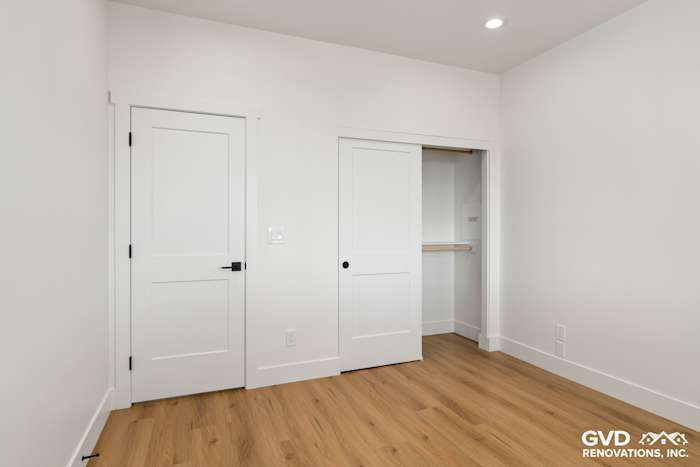 Bright, modern bedroom with white walls, sleek doors, and warm hardwood flooring in new construction home