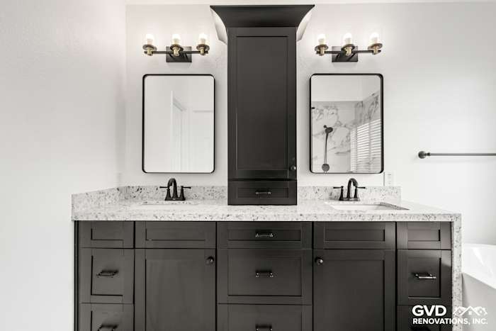 Modern bathroom featuring a double sink vanity, dark cabinetry, marble countertop, and sleek black fixtures