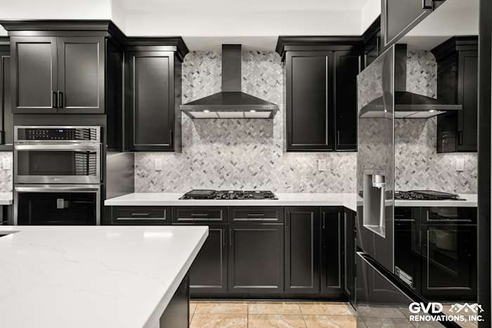 Modern black Waypoint cabinets, MSI countertops, and a herringbone backsplash in a Roseville kitchen remodel