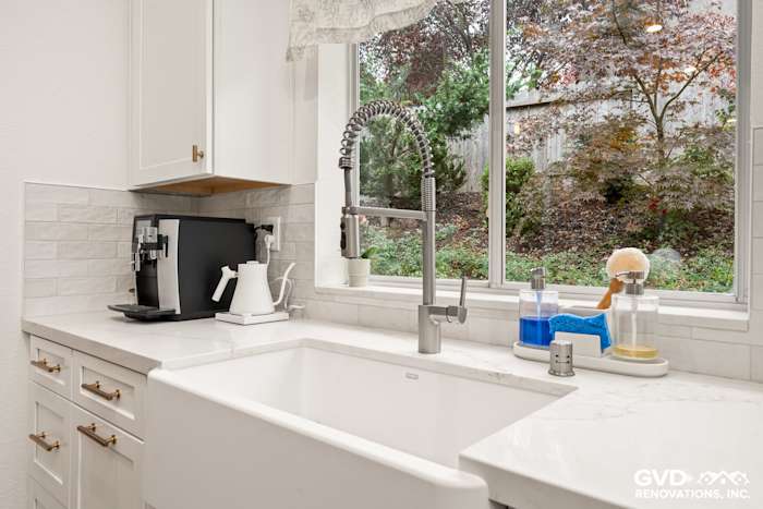 Modern kitchen sink area featuring a farmhouse sink, sleek faucet, and white cabinetry in Folsom remodel
