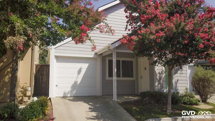 Single-story home exterior featuring Pearl Gray HardiePlank siding and Arctic White HardieTrim with flowering trees