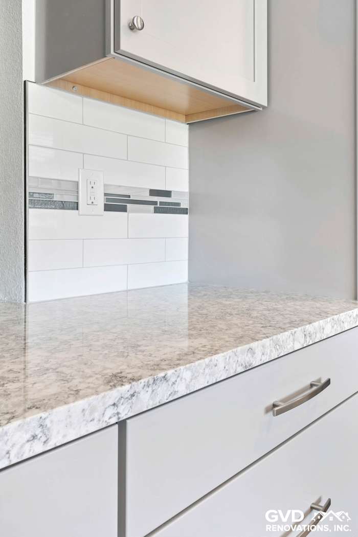 Marble countertop with gray and white subway tile backsplash in a kitchen remodel