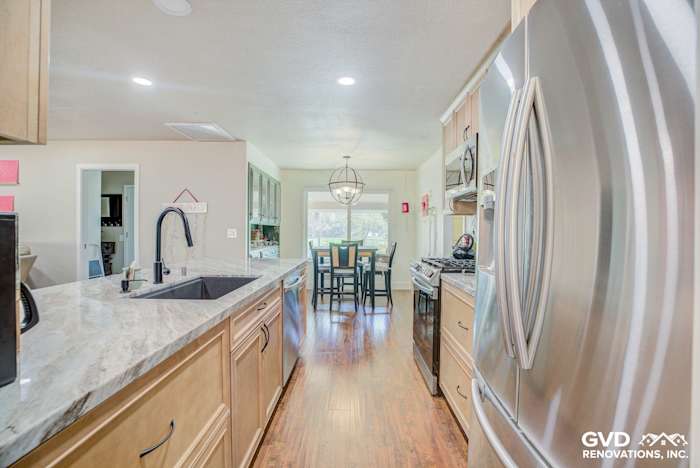 Modern kitchen with stainless steel appliances, quartz countertops, and wood floors, featuring a dining area