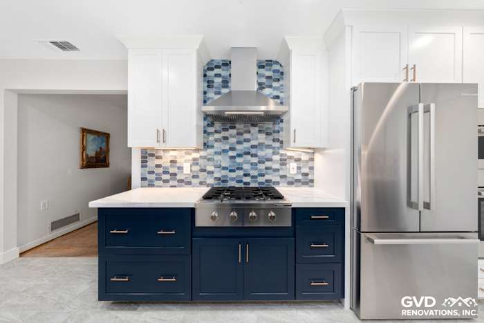 Updated kitchen with navy blue cabinets, white quartz countertops, and a stylish blue mosaic backsplash
