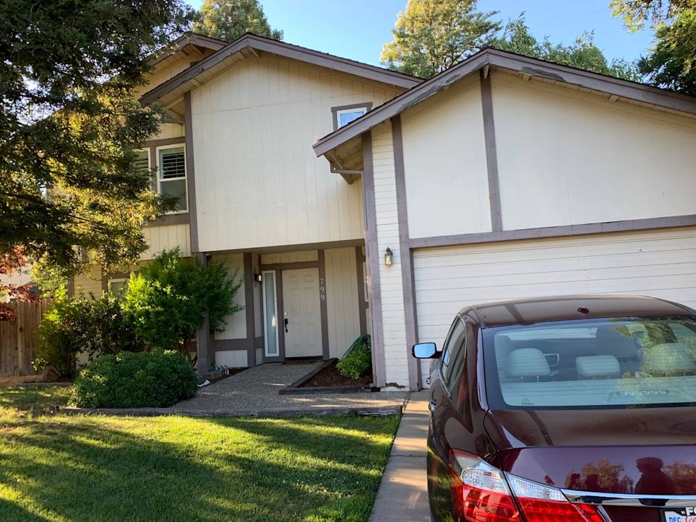 Two-story home exterior in Sacramento with beige siding, dark trim, and landscaped front yard
