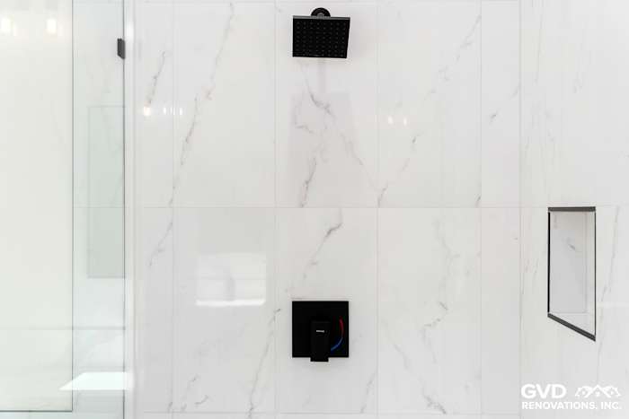 Modern bathroom shower with sleek black hardware, marble wall tiles, and frameless glass enclosure in Paradise, CA
