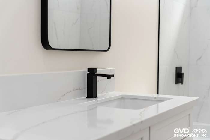 Sleek black faucet and mirror above a white marble countertop in a modern Paradise bathroom renovation