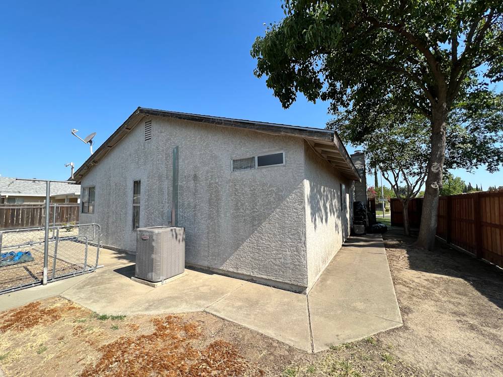 Old exterior side view of home with concrete path and gray stucco walls in Sacramento