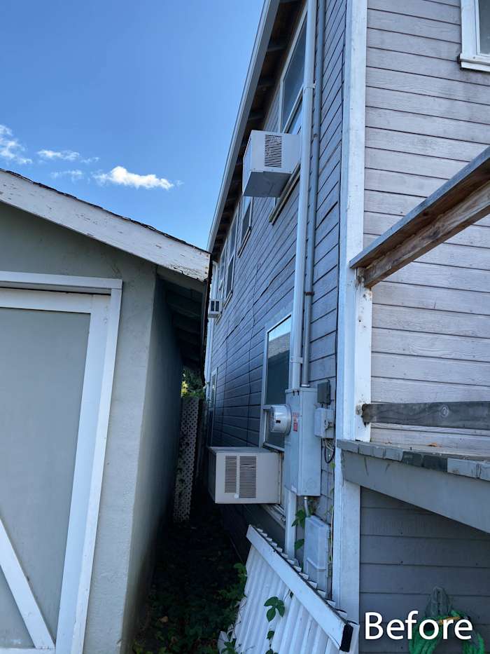 Before image of a home exterior showing old siding, utility fixtures, and narrow side area