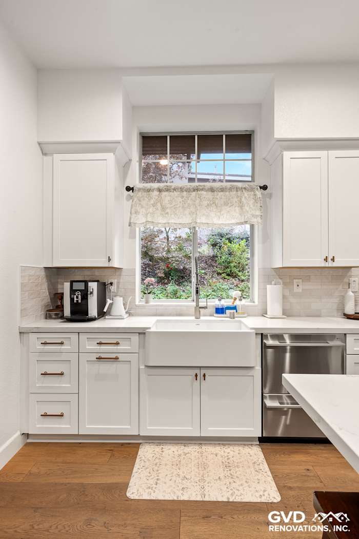 Modern kitchen with white Waypoint cabinets, farmhouse sink, wood floors, and stylish window treatment in Folsom, CA