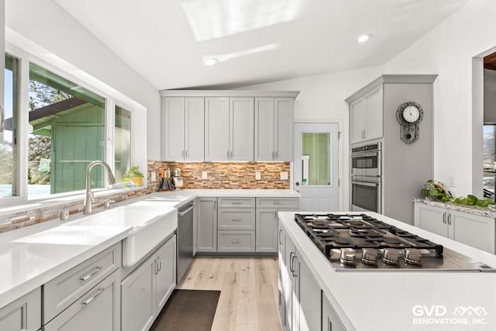 Bright and modern kitchen with gray cabinets, white quartz countertops, and a tiled backsplash in Greenwood, CA remodel