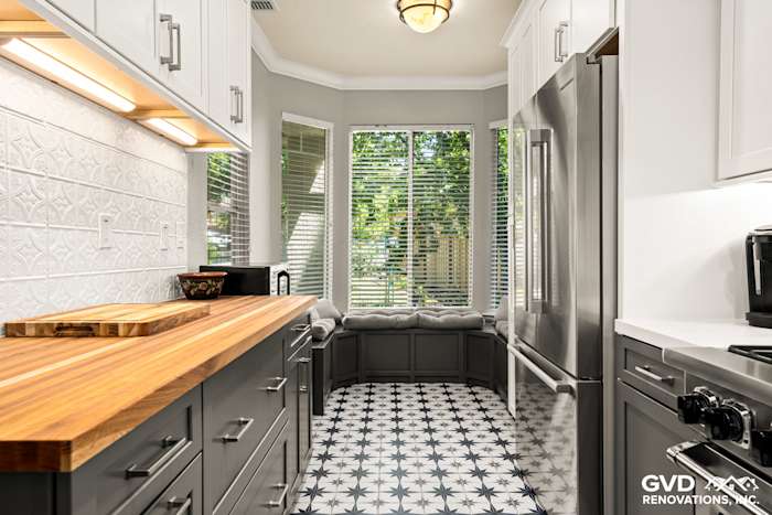Modern kitchen featuring geometric tile flooring, grey cabinetry, butcher block countertop, and bright bay window