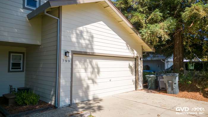 Light gray James Hardie siding and trim on a home's exterior with a garage, surrounded by landscaping