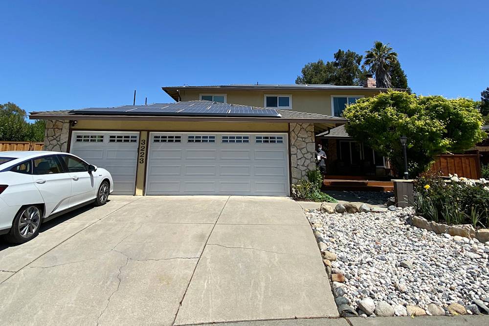 Pleasanton home featuring a stone and wood exterior, landscaped driveway, and solar panels on the roof