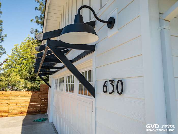 Close-up of modern home exterior featuring James Hardie Board and Batten Siding with black lighting and house numbers