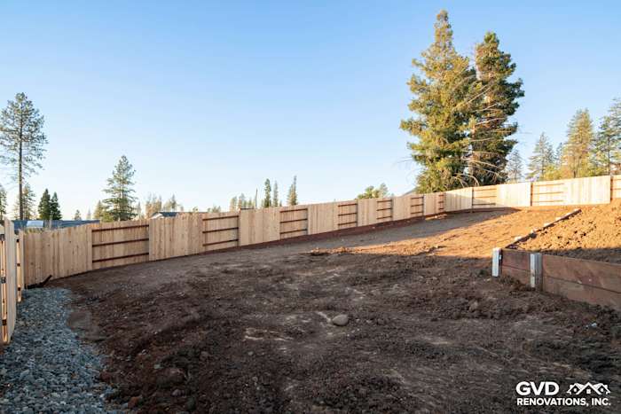 Graded landscape featuring a sloped yard with a wooden privacy fence and surrounding trees in Paradise, CA