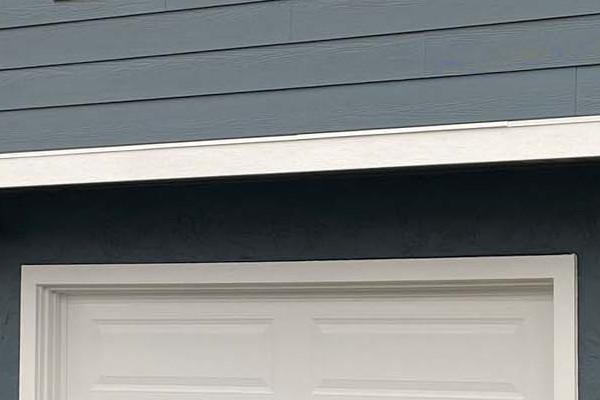 Two-story home in Daly City with new blue James Hardie siding and modern garage doors