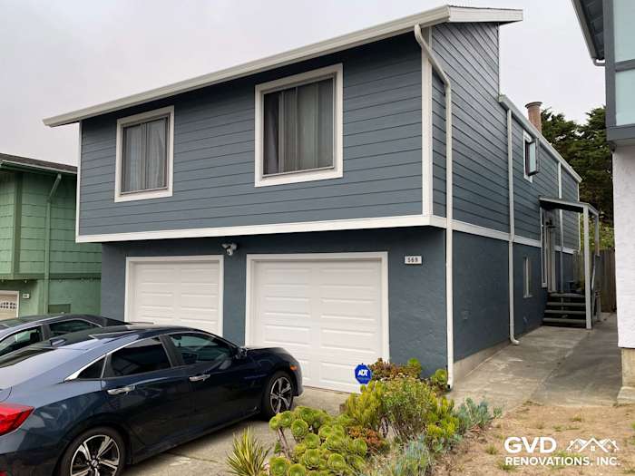 Two-story home in Daly City with new blue James Hardie siding and modern garage doors