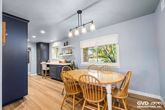 Bright kitchen with wood dining table, wooden chairs, blue cabinetry, and modern pendant lights in Fair Oaks