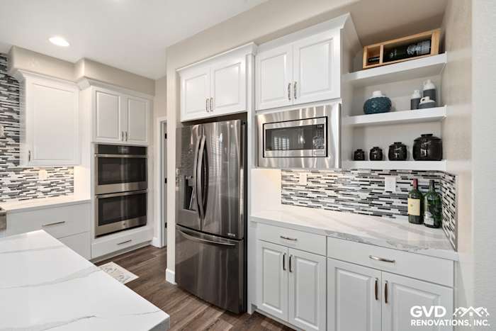 Modern kitchen with stainless steel appliances, white cabinets, quartz countertops, and glass backsplash in El Dorado Hills