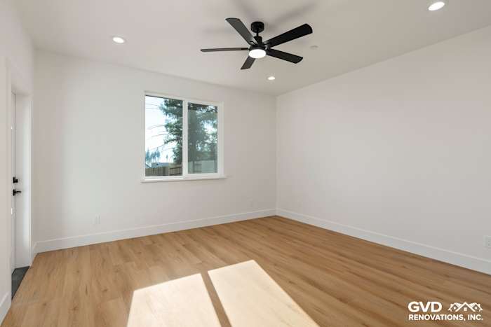 Bright bedroom featuring white walls, large window, ceiling fan, and light wood flooring in Paradise, CA