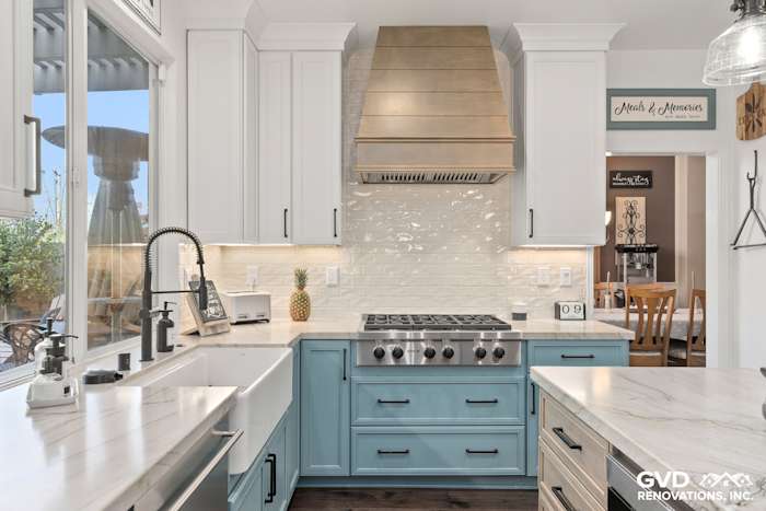 Modern kitchen with blue cabinetry, quartzite countertops, and a stainless steel range hood in Roseville